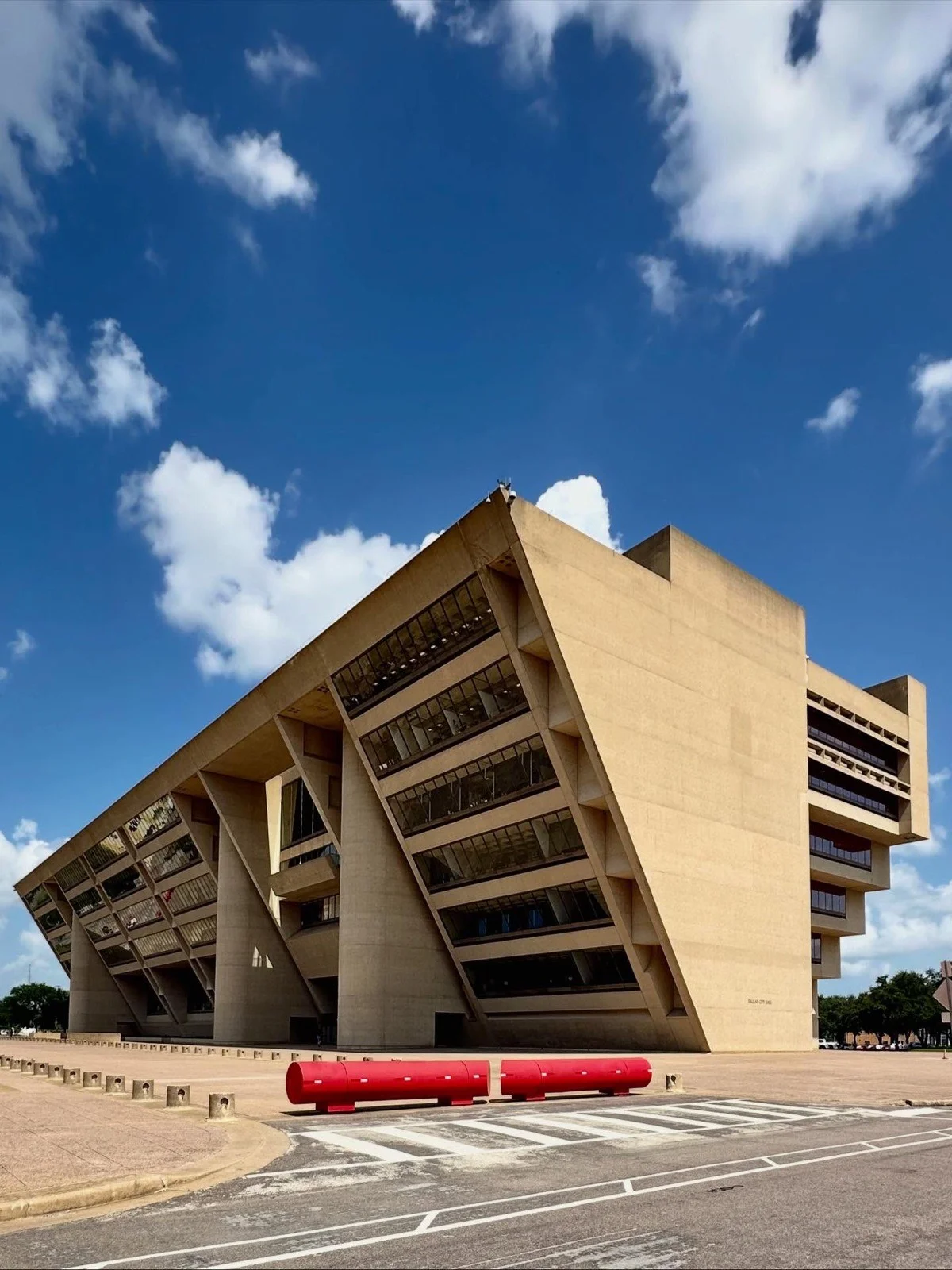 Dramatic Brutalist civic building with angular concrete forms against a blue Texas sky