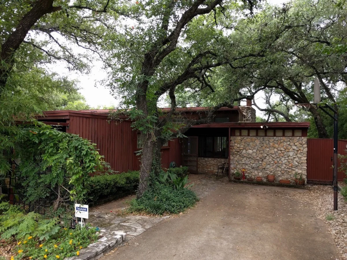 Mid-century modern ranch home with native stone and redwood among mature live oak trees in Austin Texas
